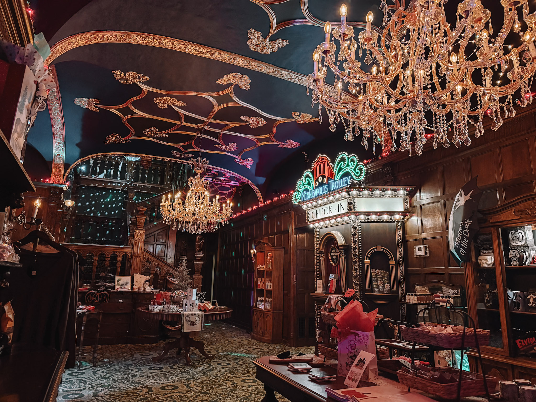 Wood-paneled room inside the Pillsbury Mansion with crystal chandeliers and a painted ceiling mural on the Pillsbury Club tour.